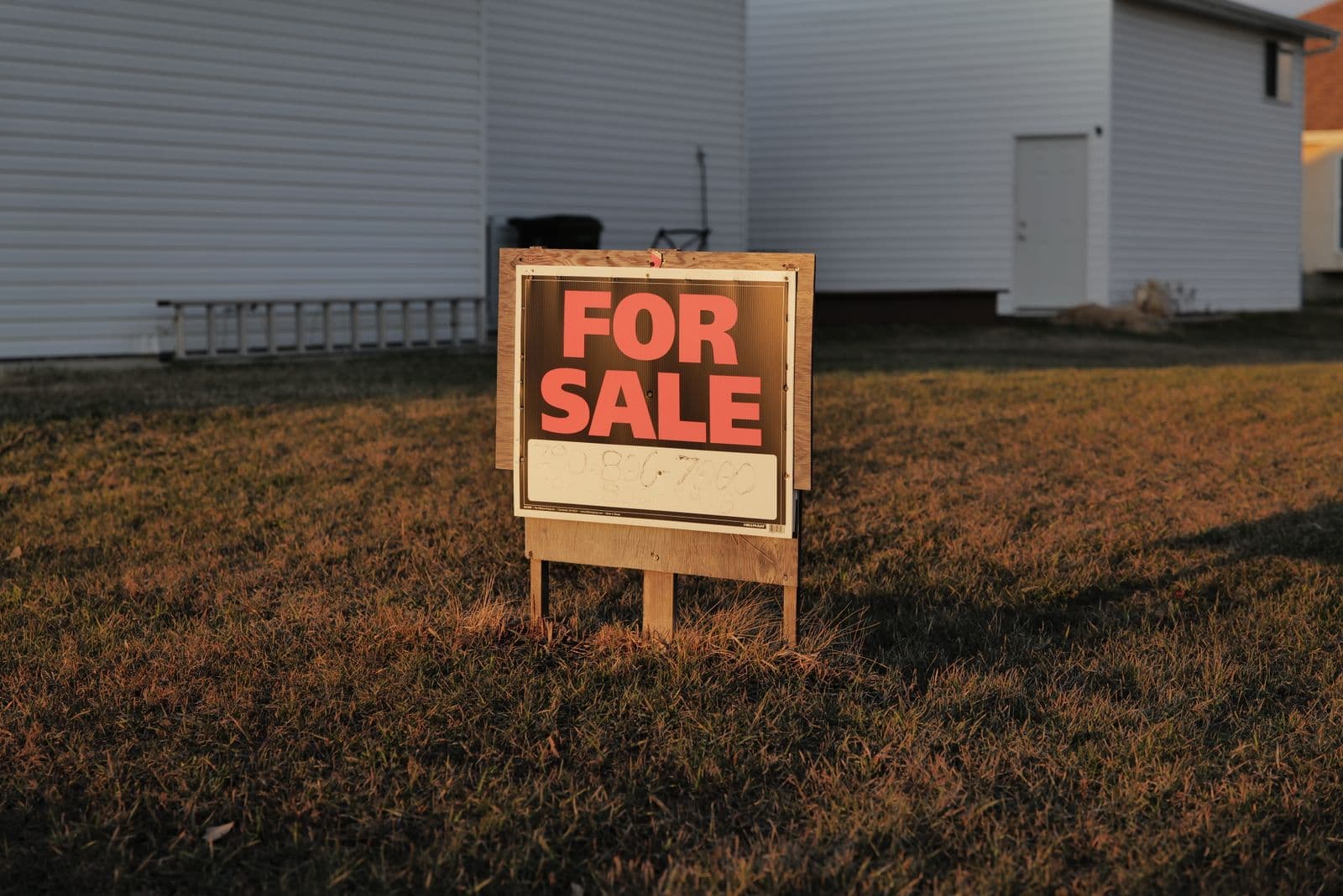 A real estate for sale sign standing in a suburban front yard