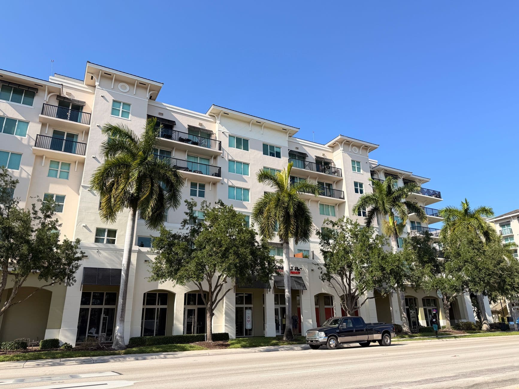A modern apartment building with palm trees on a clear sunny day.